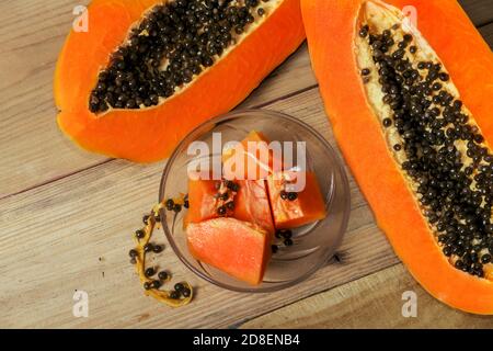 Plat d'un fruit tropical mûr communément connu sous le nom de papaye coupé en moitiés montrant toutes ses graines, et un bol en cristal avec des morceaux de fruits Banque D'Images