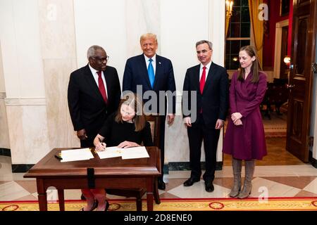 Le président américain Donald Trump regarde le juge Amy Coney Barrett signer le certificat de serment lors d'une cérémonie dans le Cross Hall de la Maison Blanche le 26 octobre 2020 à Washington. De gauche à droite se trouvent le juge associé de la Cour suprême Clarence Thomas, le président Donald Trump, l'avocat de la Maison Blanche Pat Cipolone et l'avocat adjoint de la Maison Blanche Kate Comerford Todd. Banque D'Images