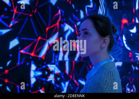 MOSCOU, RUSSIE - 01 JUIN 2019 : une femme debout devant un grand écran interactif avec une vidéo colorée d'abstat lors d'une exposition immersive moderne Banque D'Images