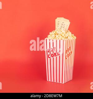 pop-corn dans un seau rouge et blanc avec billets de cinéma arrière-plan rouge Banque D'Images