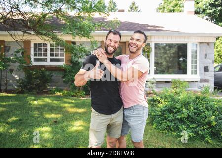 Un portrait d'un couple gay heureux à l'extérieur en face d'un nouvel achat Banque D'Images