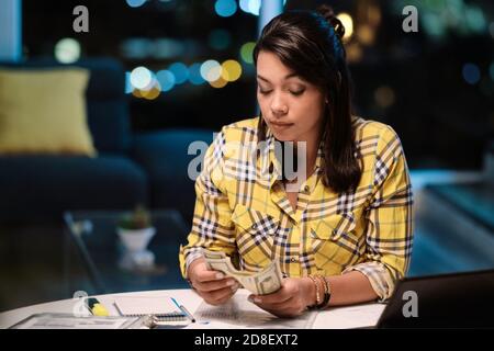 Une femme latino-américaine qui fait du budget intérieur et compte de l'argent Banque D'Images