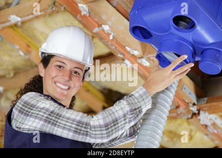 portrait d'une femme de construction qui installe le système de ventilation Banque D'Images