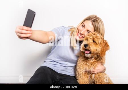 Femme avec son chien Golden Labradoodle isolé sur fond blanc Banque D'Images