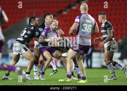 Ben Crooks (au centre) de Hull KR est attaqué par Ligi Sao (à gauche) du FC Hull lors du match de la Super League de Betfred au stade totalement Wicked, St Helens. Banque D'Images