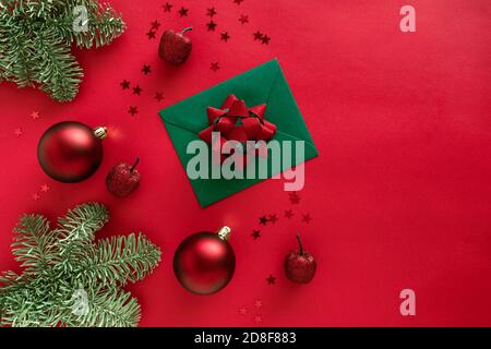 Lettre de Noël avec carte de voeux et félicitations, branches d'arbre de noël, boules, décorations scintillantes sur surface rouge. Joyeux Noël heureux Banque D'Images