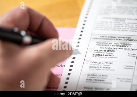 Riverside, Californie, États-Unis - 10/2020: Un homme tenant une plume sur le bulletin officiel blanc avec enveloppe sur la table lors de l'élection présidentielle de 2020. Banque D'Images