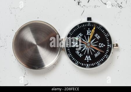 Une vieille boussole avec un couvercle en fer rayé sur la surface texturée de la table. Mise au point sélective. Banque D'Images