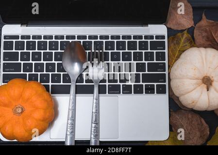 L'action de l'automne et l'Halloween des citrouilles, des feuilles sèches et ont un ordinateur portable sur fond de bois, vue du dessus shot Banque D'Images