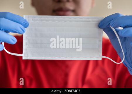 Main avec des gants chirurgicaux tenant un masque facial Banque D'Images