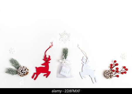 Arrangement de décorations de Noël: cerf, brindilles de sapin, baies rouges, flocons de neige et cadeau de bricolage sur blanc avec espace de copie. Banque D'Images