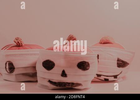 Citrouilles d'Halloween dans des masques avec des visages effrayants, covid quarantaine concept photo. Banque D'Images