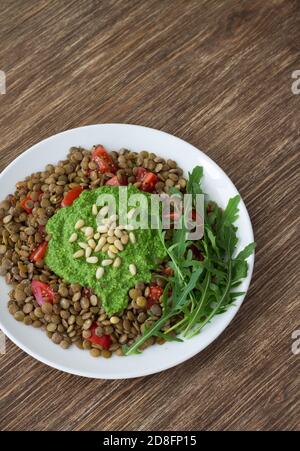 Lentilles faites maison avec tomates et sauce pesto à l'arugula sur fond de bois. Une nourriture saine et délicieuse Banque D'Images