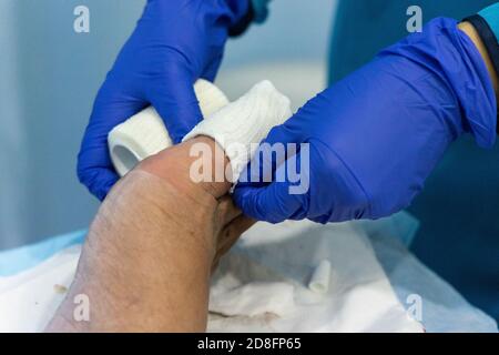 Travailleur de la santé qui allaite l'orteil avec bandage gauz après l'ongle du pied incarné chirurgie Banque D'Images