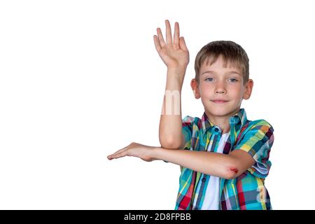 Un garçon mignon et élégant lève la main pour répondre en classe. Un enfant heureux contre un tableau blanc. Concept d'éducation, de retour à l'école Banque D'Images