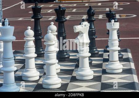 Échecs géants sur grand échiquier dans le parc de la rue. Figurines en plastique gros plan, mise au point sélective. Banque D'Images