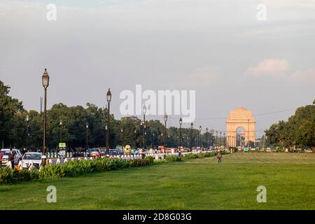 Vue sur l'emblématique porte de l'Inde et la route Rajpath avec un beau coucher de soleil en arrière-plan, la vie de rue à Delhi, les véhicules sur la route. Banque D'Images