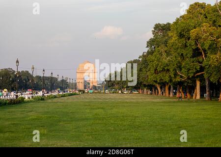 Vue sur l'emblématique porte de l'Inde et la route Rajpath avec un beau coucher de soleil en arrière-plan, la vie de rue à Delhi, les véhicules sur la route. Banque D'Images