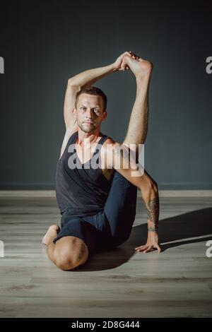 Yogi homme a soulevé sa jambe derrière sa tête. Posture du yoga sur les jambes. Banque D'Images