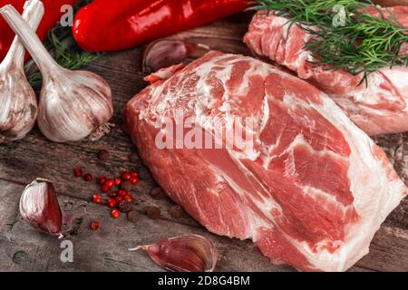 morceau de col de porc cru sur une table en bois. Filet de porc aux épices, au romarin et au poivre rouge sur fond de bois sombre. Vue rapprochée sur le dessus Banque D'Images