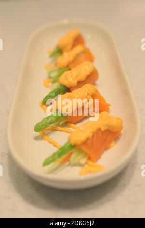 Saumon roulé avec asperges et concombres frais garnis de sauce aux crevettes sur le dessus Banque D'Images