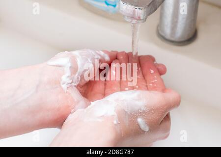 Gros plan sur le lavage des mains des femmes avec du savon sous l'eau courante. Protection contre les pandémies COVID 19 Banque D'Images