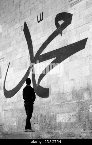 Jeune homme regardant la calligraphie arabe signifiant « Prophète Muhammad » Sur le mur de la vieille mosquée d'Edirne Banque D'Images