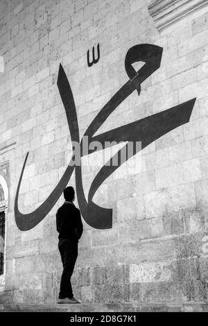 Jeune homme regardant la calligraphie arabe signifiant « Prophète Muhammad » Sur le mur de la vieille mosquée d'Edirne Banque D'Images