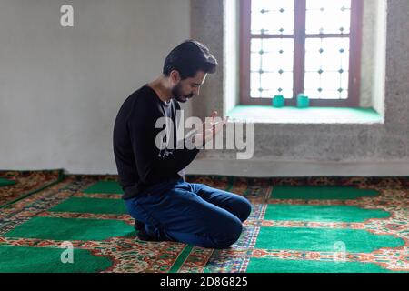 Un jeune homme moustaché priant dans une mosquée Banque D'Images