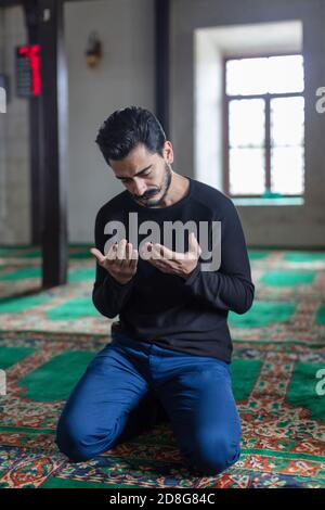 Un jeune homme moustaché priant dans une mosquée Banque D'Images