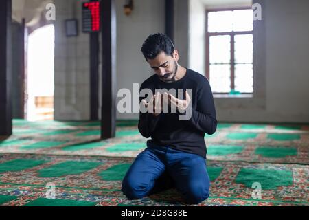 Un jeune homme moustaché priant dans une mosquée Banque D'Images