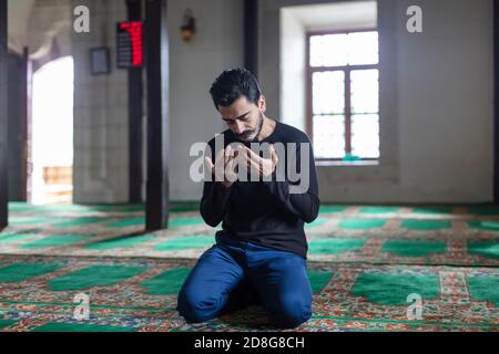 Un jeune homme moustaché priant dans une mosquée Banque D'Images