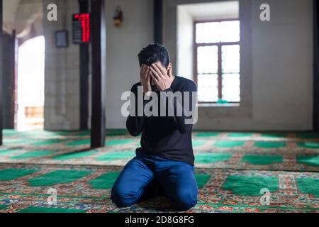 Un jeune homme moustaché priant dans une mosquée Banque D'Images