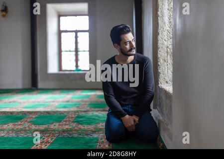 Un jeune homme moustaché priant dans une mosquée Banque D'Images