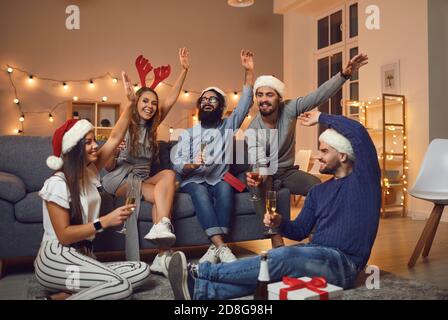 Joyeux jeunes amis qui boivent du champagne et qui se souhaitent mutuellement Joyeux Noël et bonne année Banque D'Images