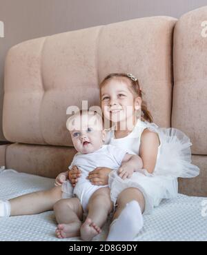 Deux petites filles, sœurs jouant à la maison, sur le canapé, s'embrassant, isolement, vacances, week-end à la maison, socialisation Banque D'Images