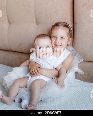 Deux petites filles, sœurs jouant à la maison, sur le canapé, s'embrassant, isolement, vacances, week-end à la maison, socialisation Banque D'Images