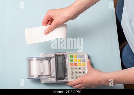 Gros plan sur les mains d'une jeune femme qui déchirent un chèque une caisse après l'achat d'un produit sur un marché ou magasin Banque D'Images