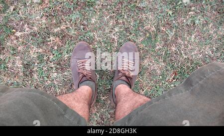 Jeune homme dans son short, avec ses chaussures debout sur le sol de l'herbe verte Banque D'Images