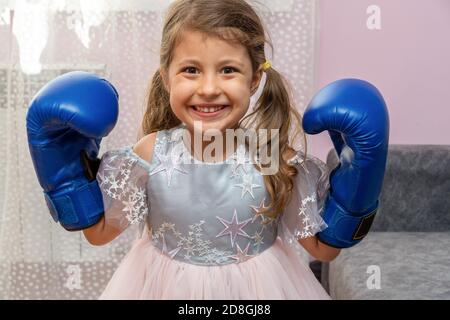 Petite fille portant des gants de boxe bleus et une robe de fête avec des étoiles Banque D'Images