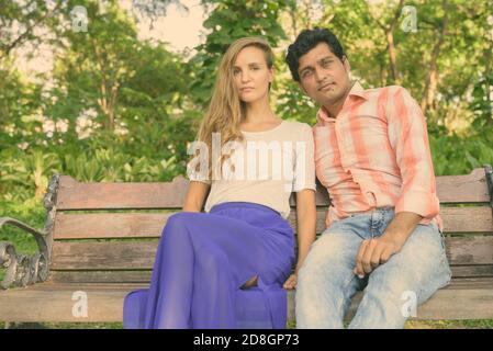 Multi Ethnic couple sur banc en bois dans l'amour à Green Park pacifique Banque D'Images