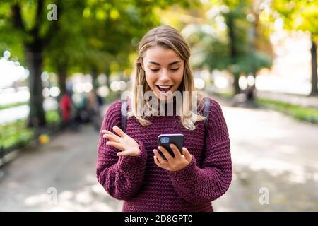 Surpris woman receiving nouvelle choquante sur un téléphone intelligent dans la rue Banque D'Images