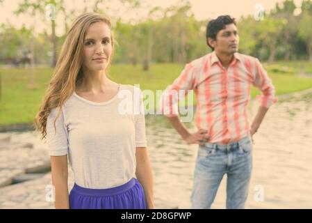 Belle femme avec l'homme et la pensée indienne debout sur sentier en pierre au milieu du lac dans le parc verdoyant paisible Banque D'Images