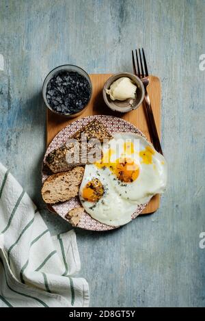 assiette d'œufs frits avec pain aux graines, sel noir et beurre, pain grillé. Par le haut Banque D'Images
