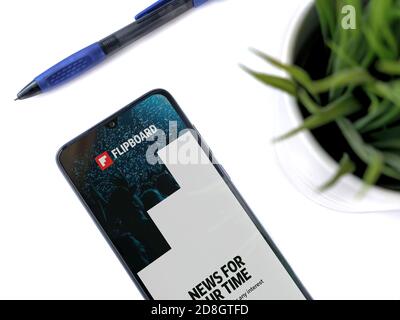 LOD, Israël - 8 juillet 2020 : espace de travail moderne et minimaliste avec smartphone mobile noir et écran de lancement de l'application Flipboard avec logo sur fond blanc Banque D'Images