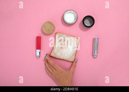 Crop femme avec des produits de maquillage sur table rose Banque D'Images