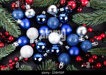 Vue de dessus des boules de noël, des perles rouges et des branches de pin sur fond noir Banque D'Images