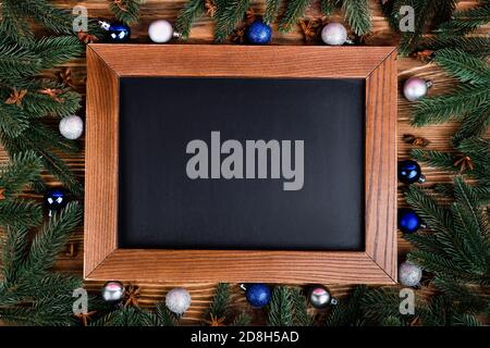 Plat avec tableau blanc, boules, branches de pin et étoiles anis sur fond de bois brun Banque D'Images