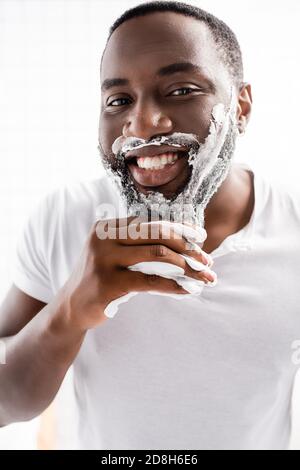 homme afro-américain souriant avec mousse à raser sur le visage appareil photo