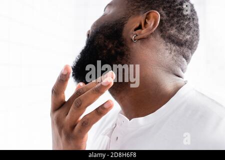 homme afro-américain appliquant un traitement pour renforcer la croissance de la barbe Banque D'Images